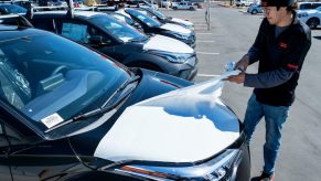 A car lot detailer pulls the wraps off a new car