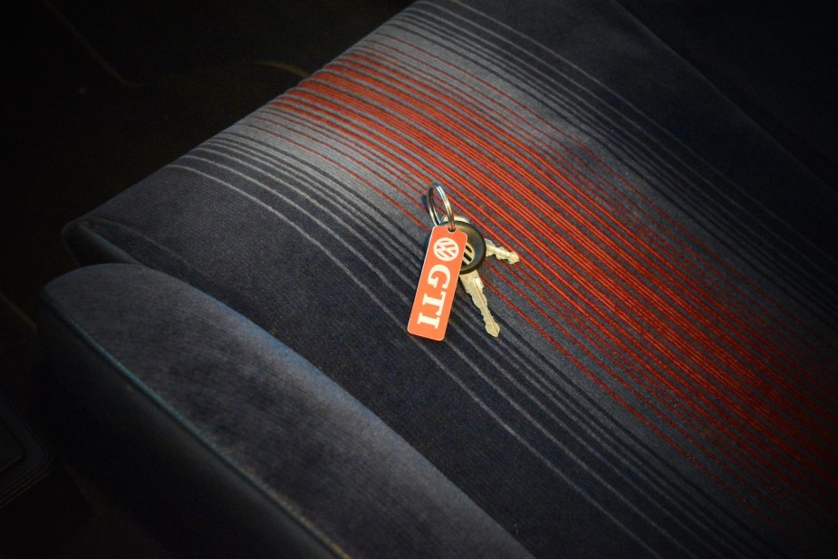 A set of Volkswagen keys on the cloth seats of a locked car.