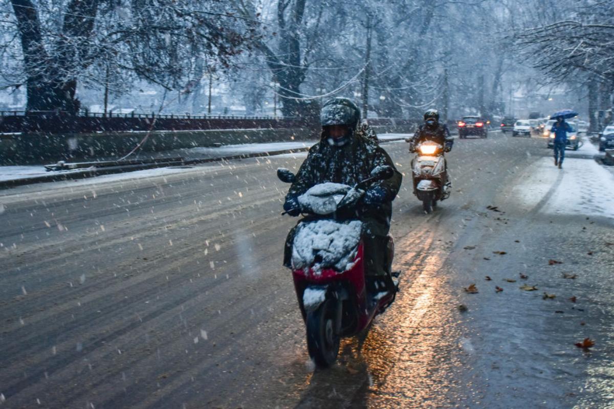 Motorcycles driving on a snowy road in the winter.