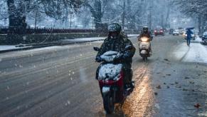 Motorcycles driving on a snowy road in the winter.