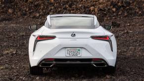 A rear shot of the trunk, bumper, and taillights on a 2024 Lexus LC 500 grand tourer parked on clumps of dirt