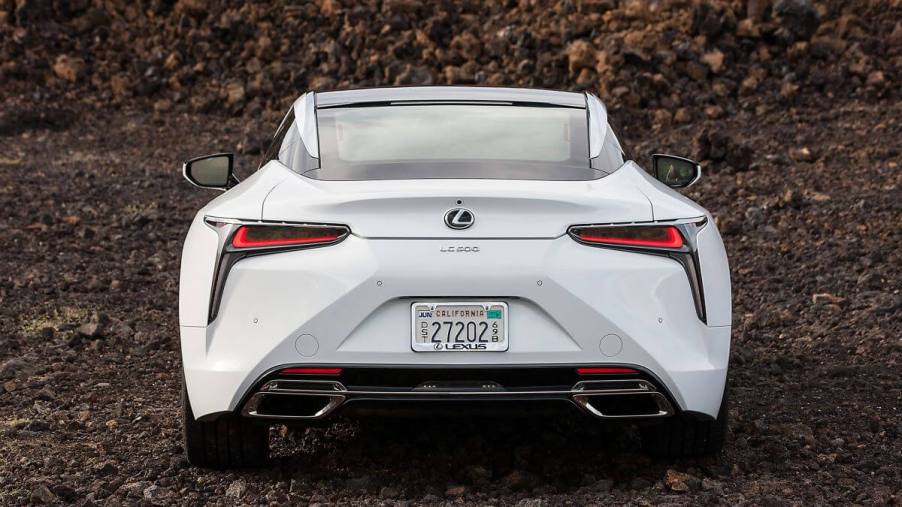 A rear shot of the trunk, bumper, and taillights on a 2024 Lexus LC 500 grand tourer parked on clumps of dirt