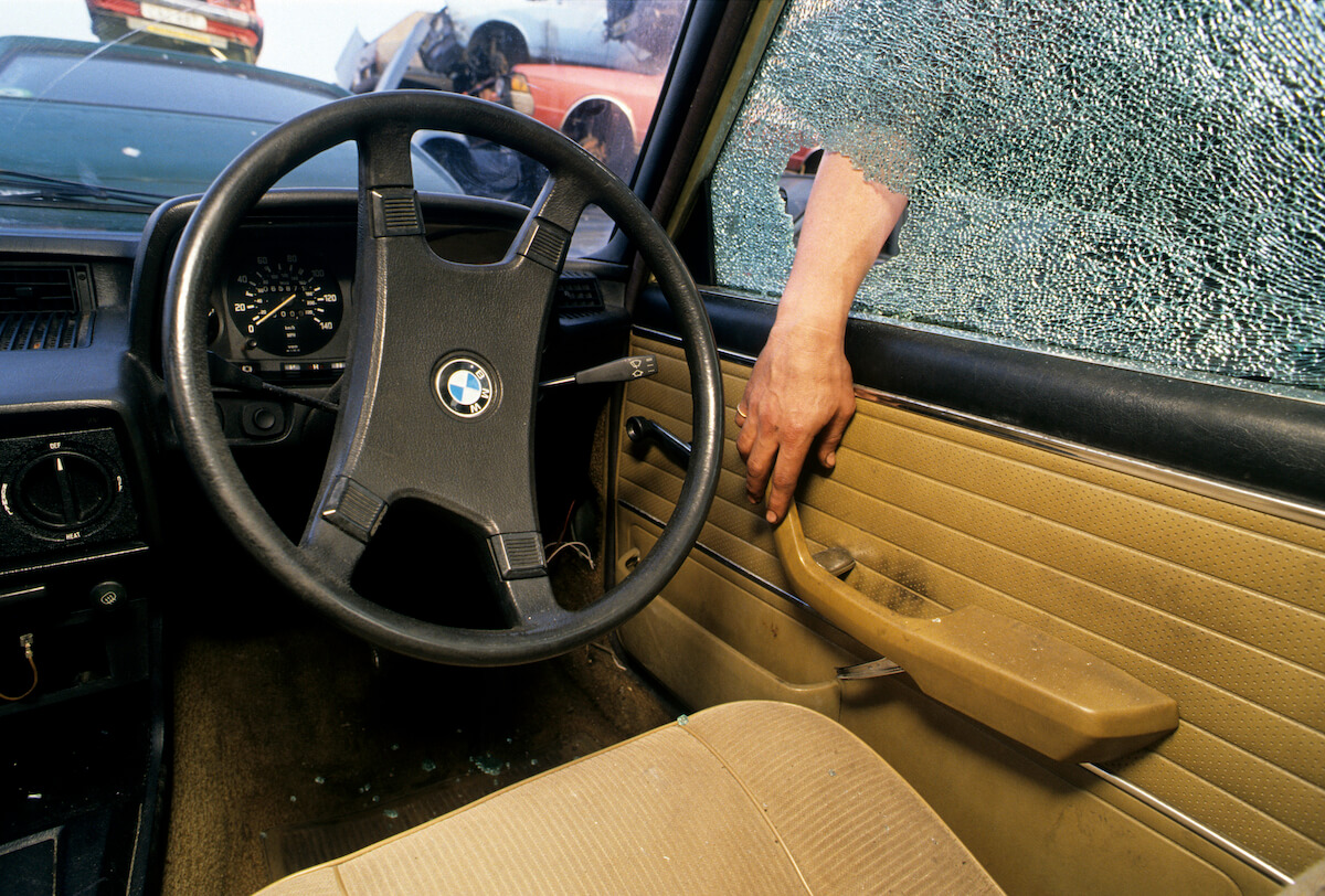 A car thief breaks into a car through the window