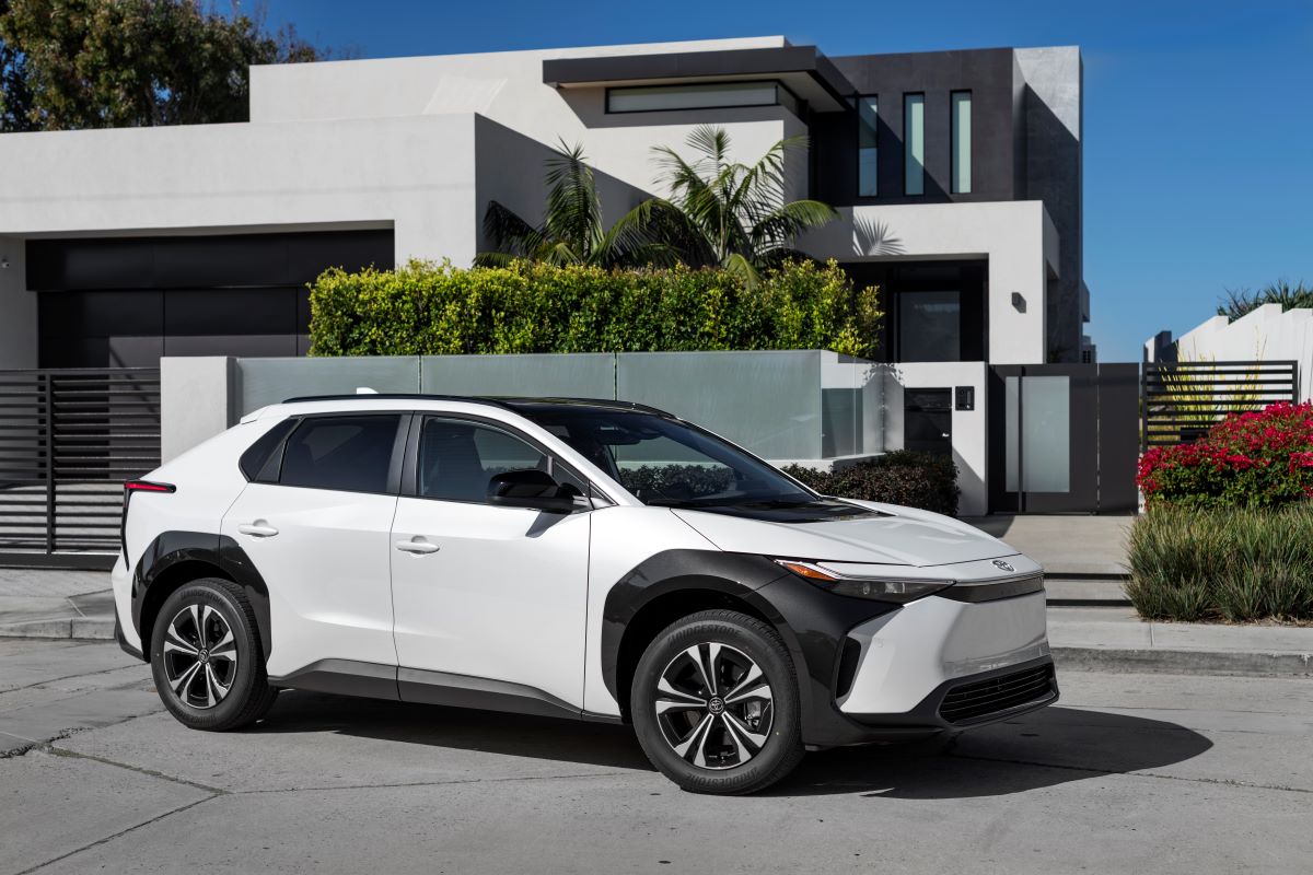 A 2023 Toyota bZ4X XLE compact electric SUV with FWD in Wind Chill Pearl parked outside a luxury home