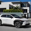 A 2023 Toyota bZ4X XLE compact electric SUV with FWD in Wind Chill Pearl parked outside a luxury home