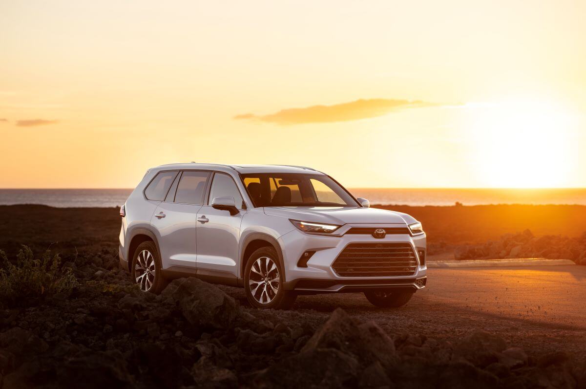 A 2024 Toyota Grand Highlander Limited midsize SUV model parked in the wild as the sun sets behind it