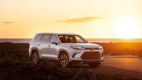 A 2024 Toyota Grand Highlander Limited midsize SUV model parked in the wild as the sun sets behind it