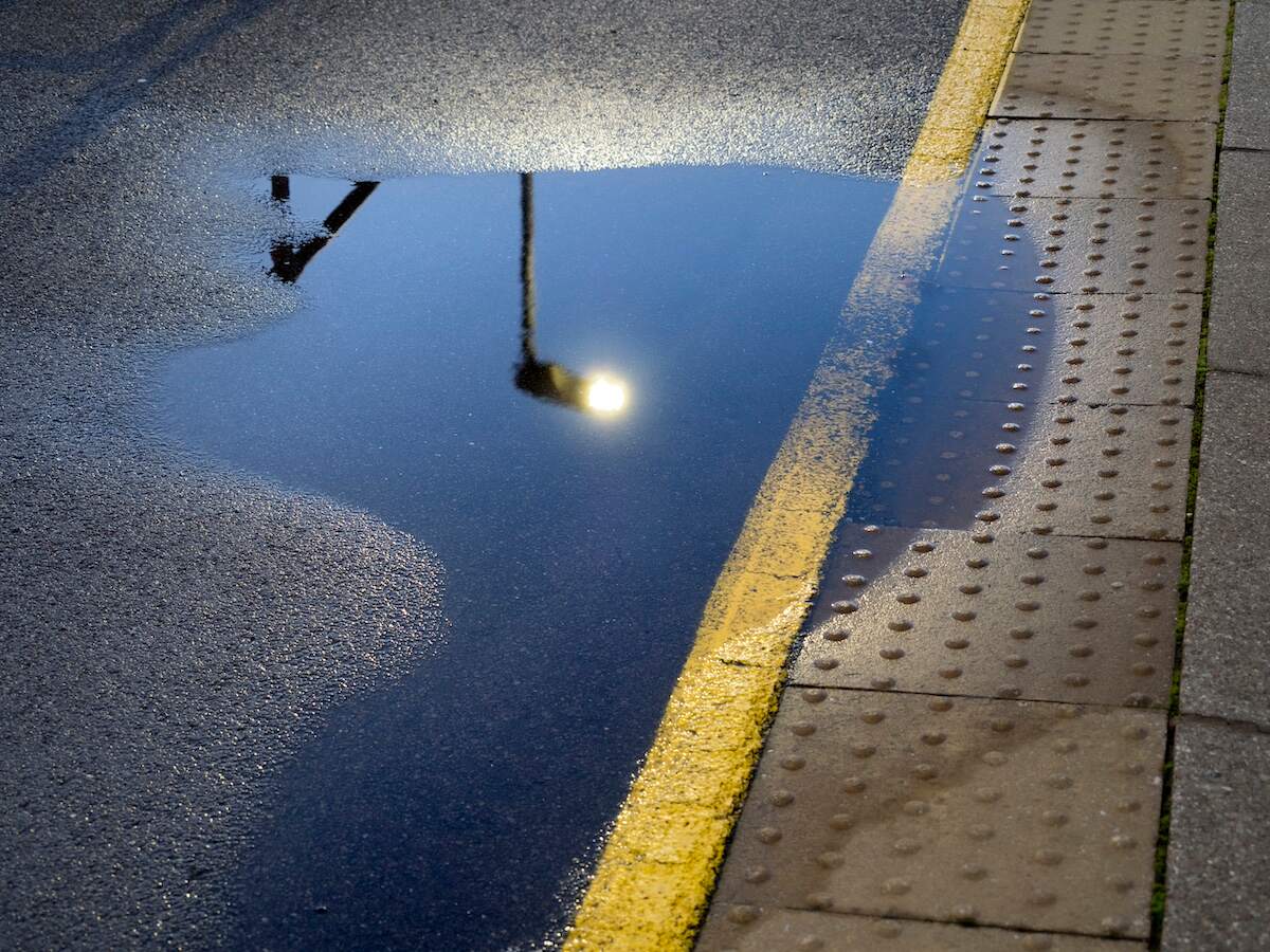 A yellow line road marker runs through a puddle