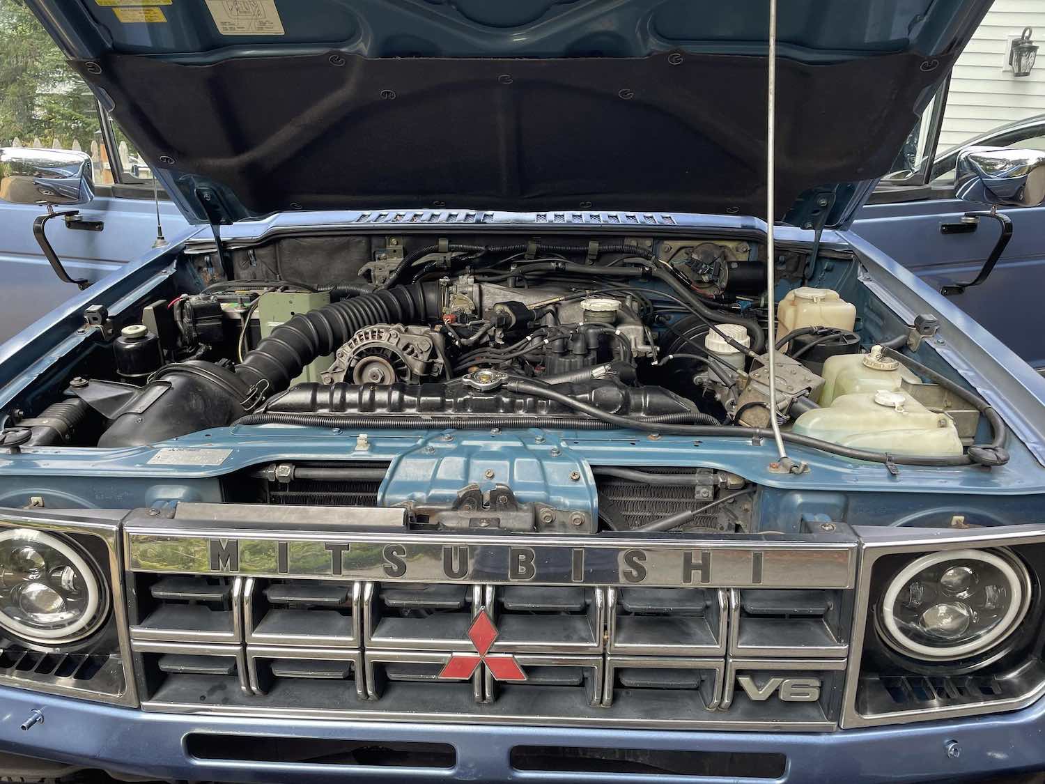 The V6 in the engine bay of a first-gen Mitsubishi Montero SUV with its hood up.