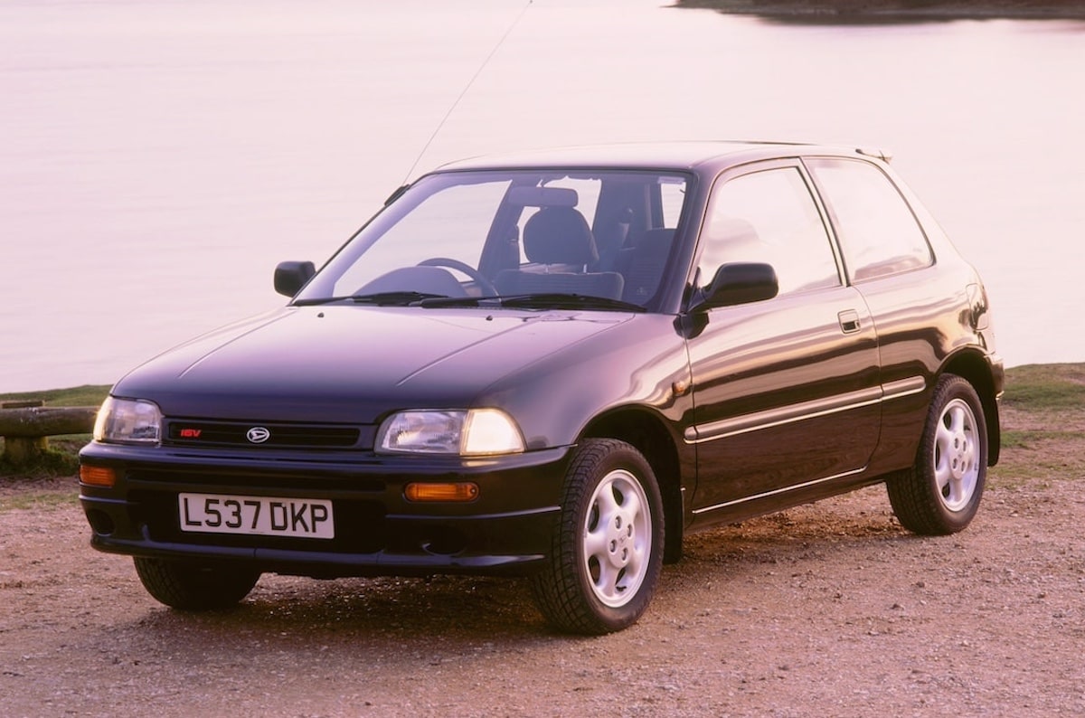 A 1994 Daihatsu Charade GTI parked on gravel in front of a lake