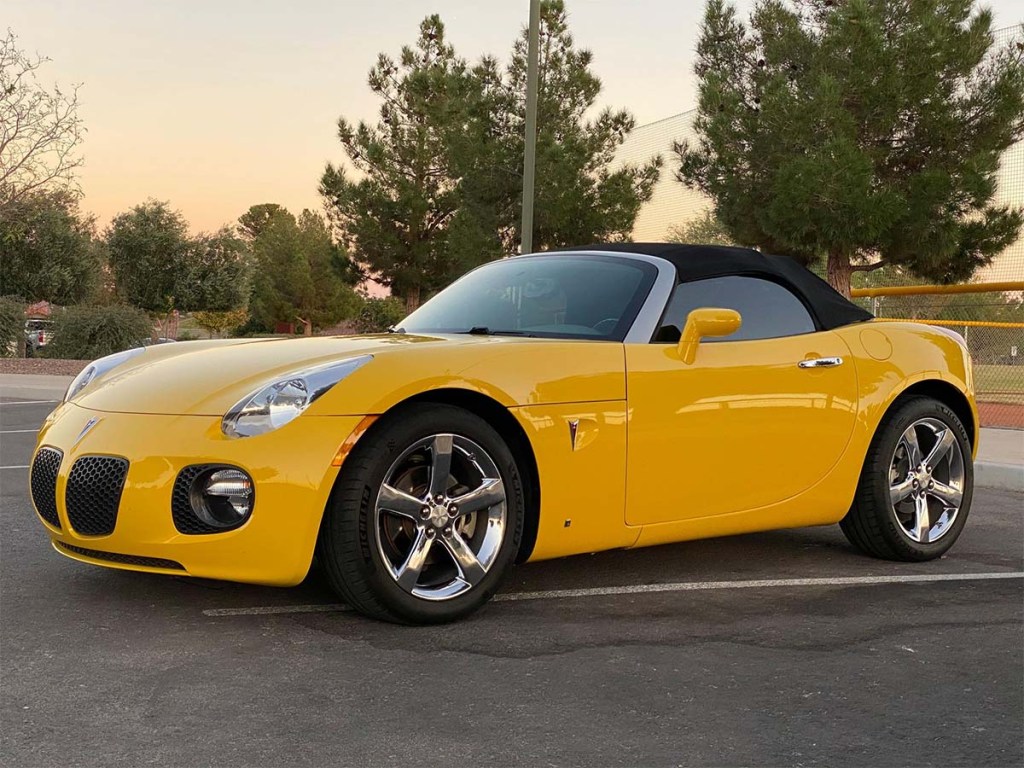 Front 3/4 shot in front of trees of Yellow 2008 Pontiac Solstice GXP turbocharged convertible sports car sold on Cars and Bids for under $15,000