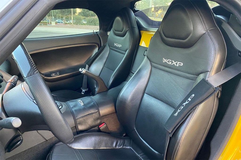 Black leather interior with custom carbon fiber steering wheel inside Yellow 2008 Pontiac Solstice GXP turbocharged convertible sports car sold on Cars and Bids for under $15,000