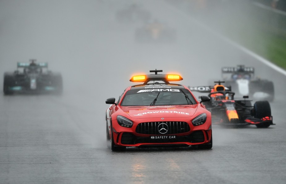 A red Mercedes-Benz FIA safety car leads two Formula 1 race cars during the 2021 Belgian Grand Prix