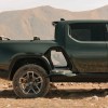 A green Rivian R1T gear tunnel is shown open in right profile view with the desert and mountains in the background