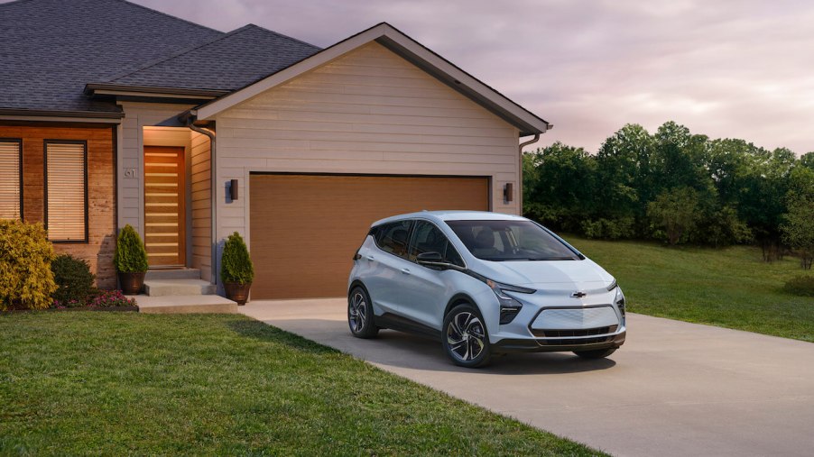 A white Chevy Bolt parked outside of a suburban house. Chevy Bolt complaints are pretty prevalent.