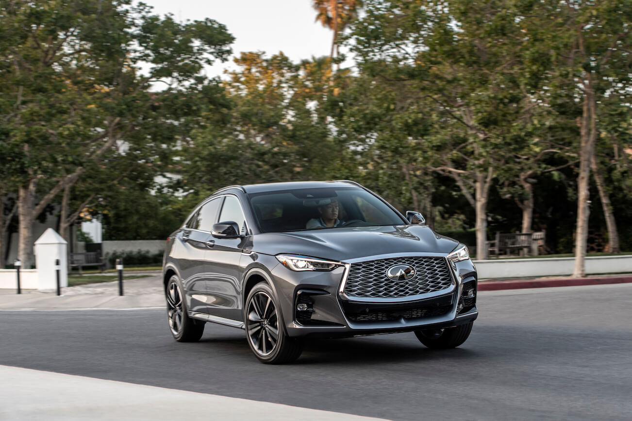 The 2023 Infiniti QX55 in gray driving down a city street.