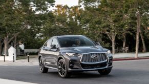 The 2023 Infiniti QX55 in gray driving down a city street.