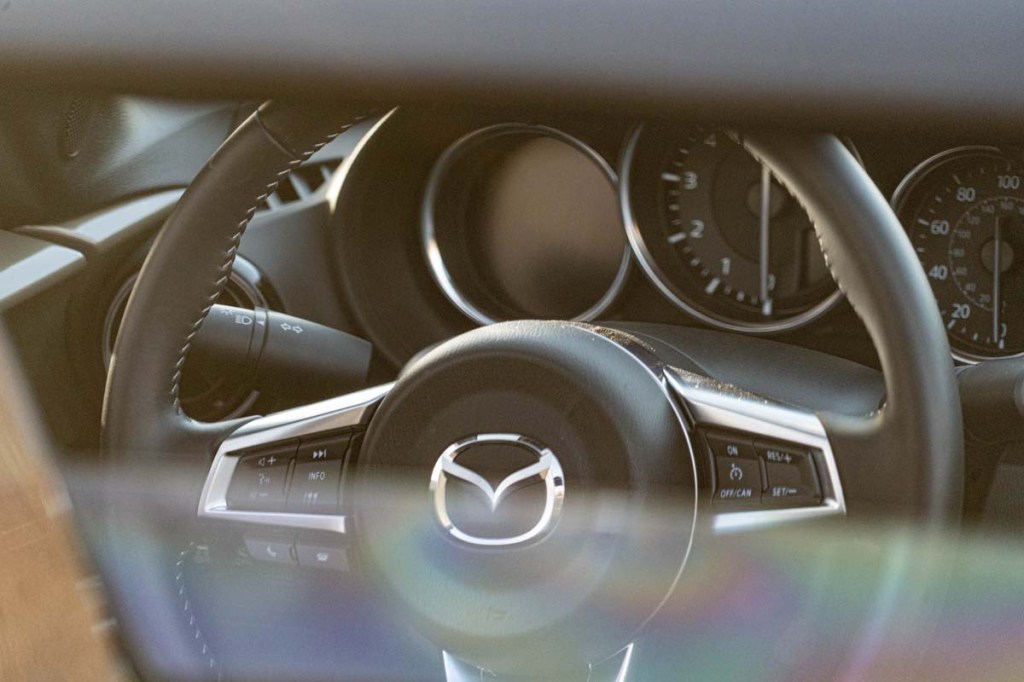 Black Mazda Miata steering wheel shot through back window with top down