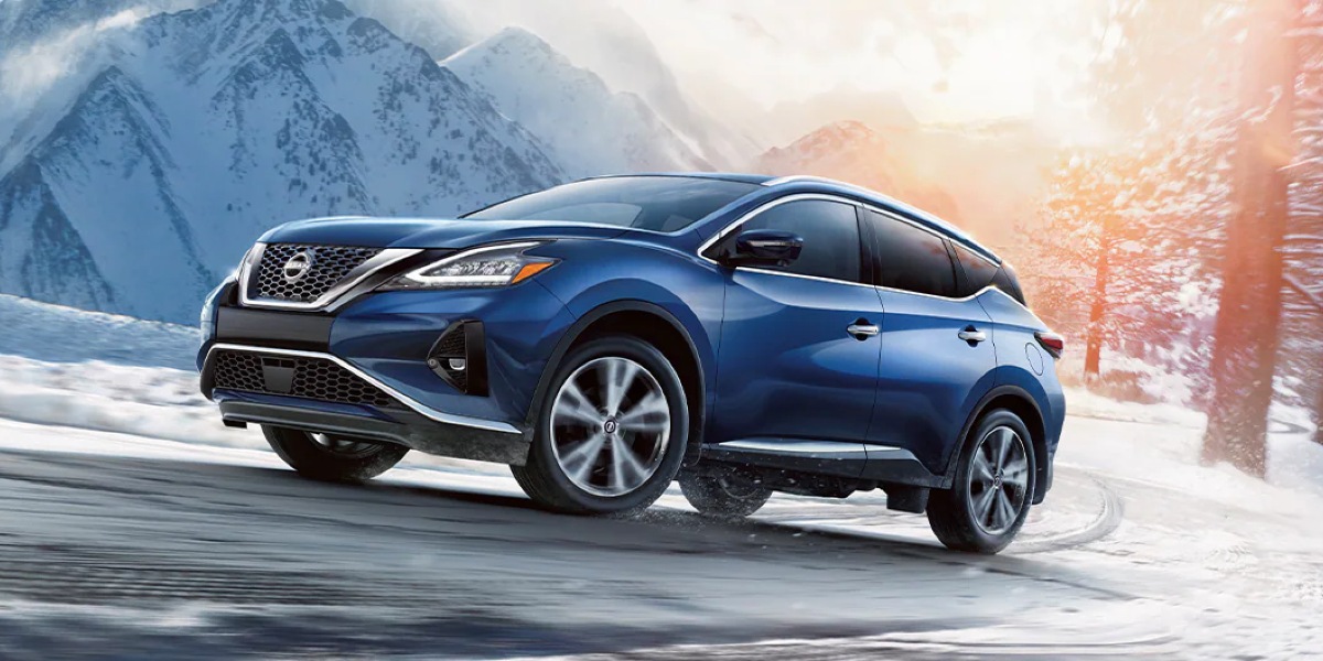 A blue 2023 Nissan Murano midsize SUV is driving uphill.