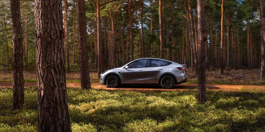 A gray 2023 Tesla Model Y small electric SUV is driving off-road.