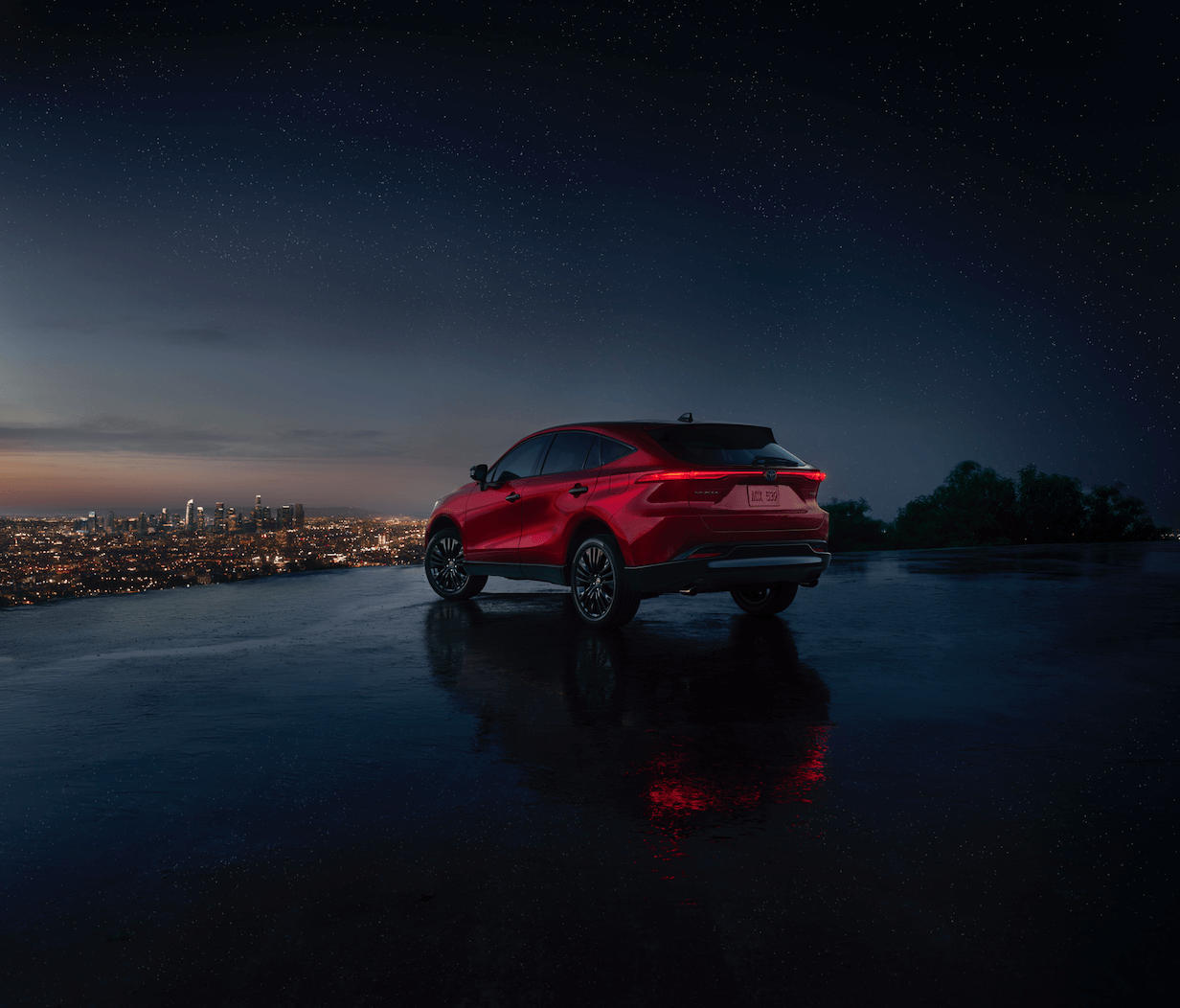The rear shot of a 2023 Toyota Venza Nightshade overlooking the city at night on a cliff. The Toyota Venza's resale value is pretty high.