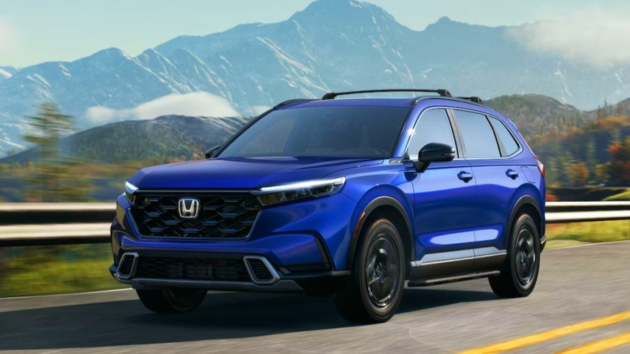A blue 2024 Honda CR-V small SUV is driving on the road.