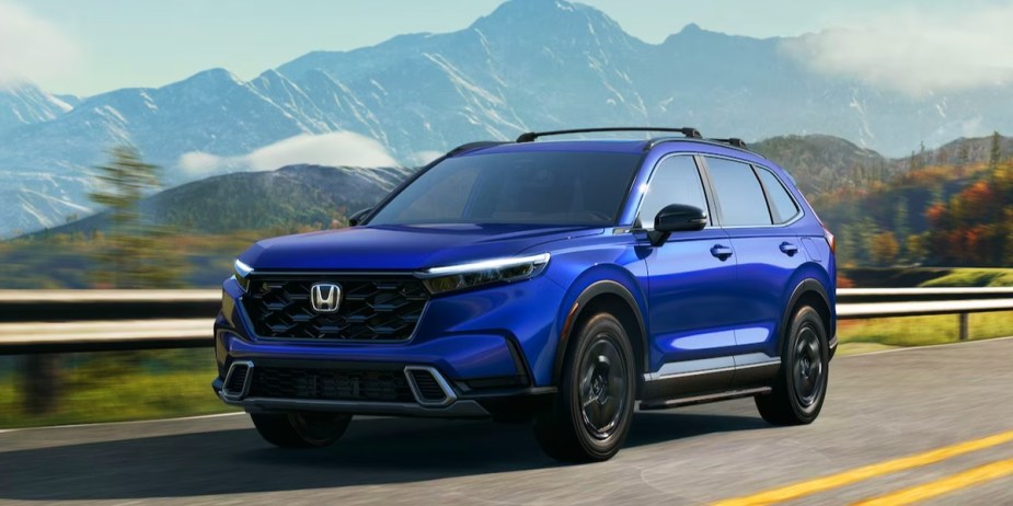 A blue 2024 Honda CR-V small SUV is driving on the road.