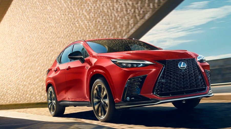 A red 2024 Lexus NX small luxury SUV is driving on the road.