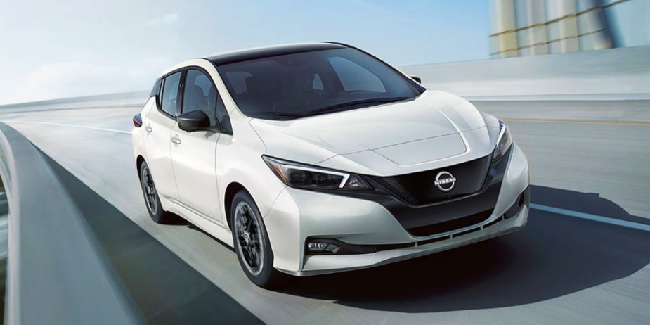 A white 2024 Nissan Leaf electric car is driving. 