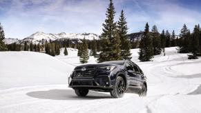A 2024 Subaru Ascent midsize SUV model traversing in the snow among pine trees and mountains