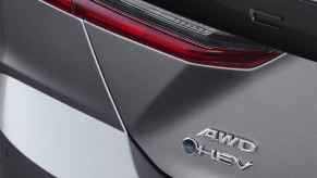 The right rear corner of a charcoal 2025 Toyota Camry XSE is shown with AWD and HEV badges
