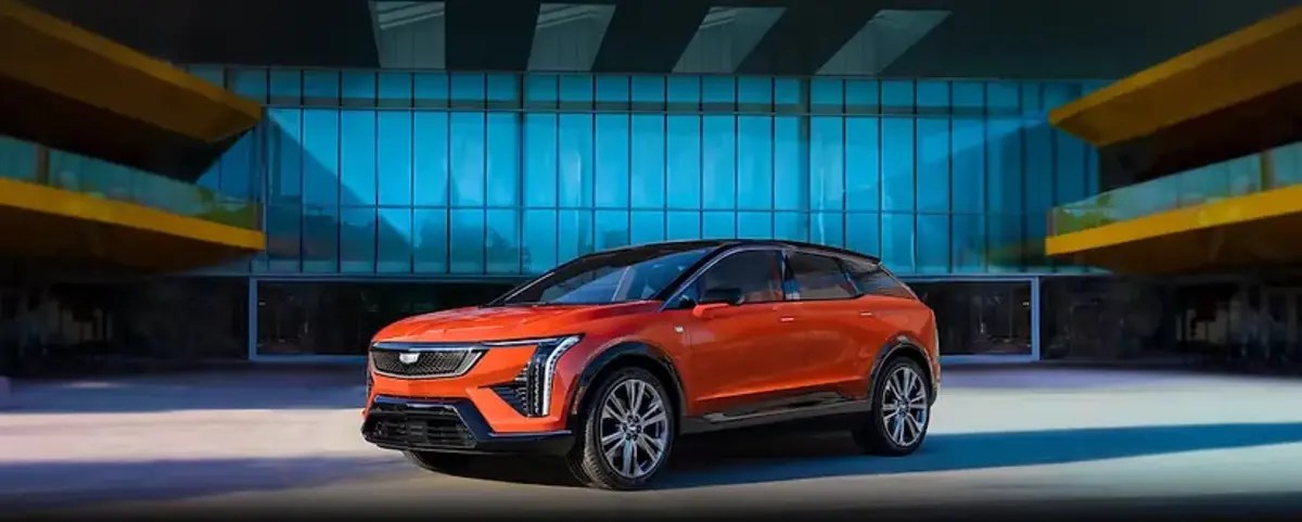 Orange 2025 Cadillac Optiq EV SUV with blue background