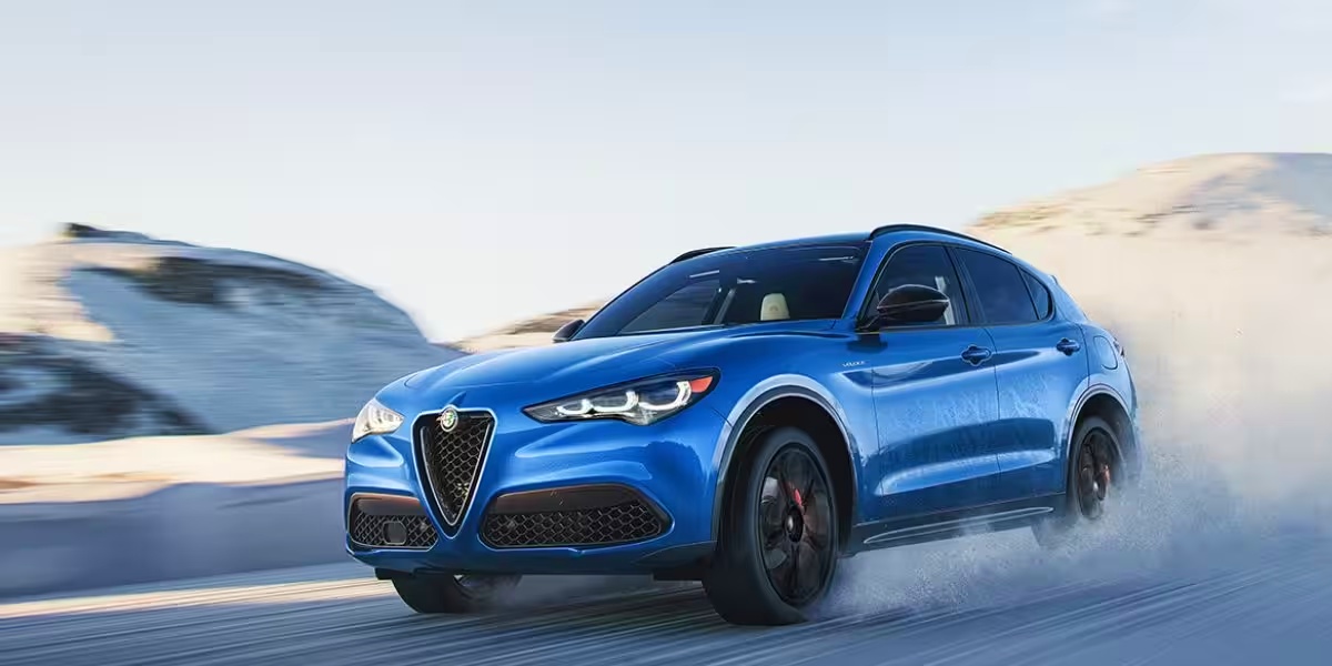 A blue Alfa Romeo Stelvio subcompact luxury SUV is driving off-road.