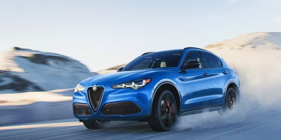 A blue Alfa Romeo Stelvio subcompact luxury SUV is driving off-road. 