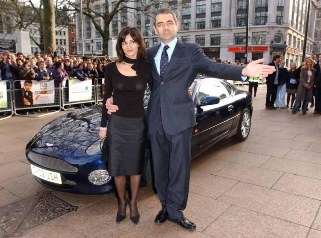 Rowan Atkinson with his wife Sunetra stand next to an Aston Martin DB7 Vantage GT car to promote Johnny English, a James Bond 007 parody.