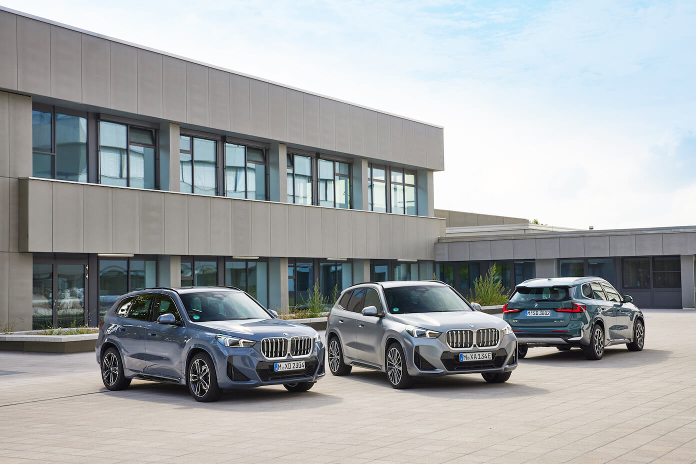 The 2023 BMW X1 among other SUVs in the lineup in front of a modern building. BMW SUV sales are struggling this year.