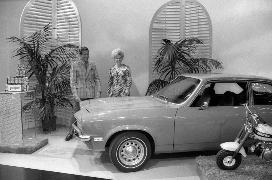 Bob Barker and a contestant stand behind a Chevy Vega car on 'The Price Is Right' stage in 1972
