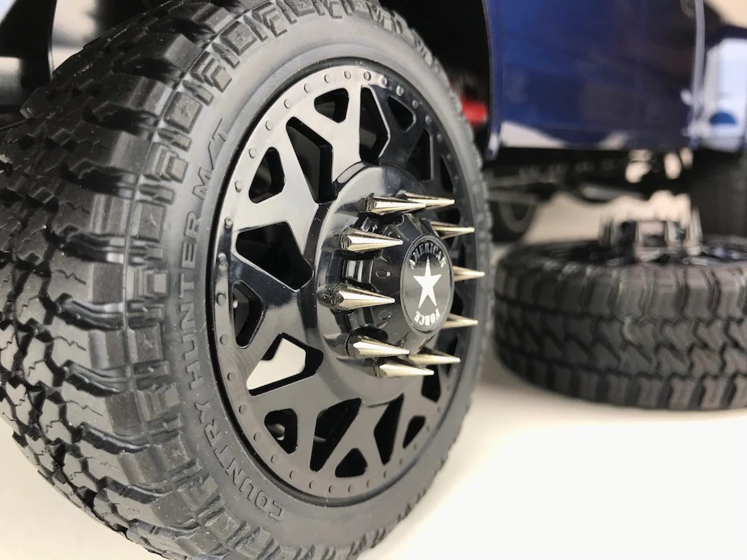 The spiked lug nuts on the aftermarket rims of a lifted pickup truck.