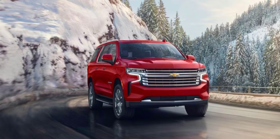 A red Chevrolet Suburban full-size SUV is driving on the road. 