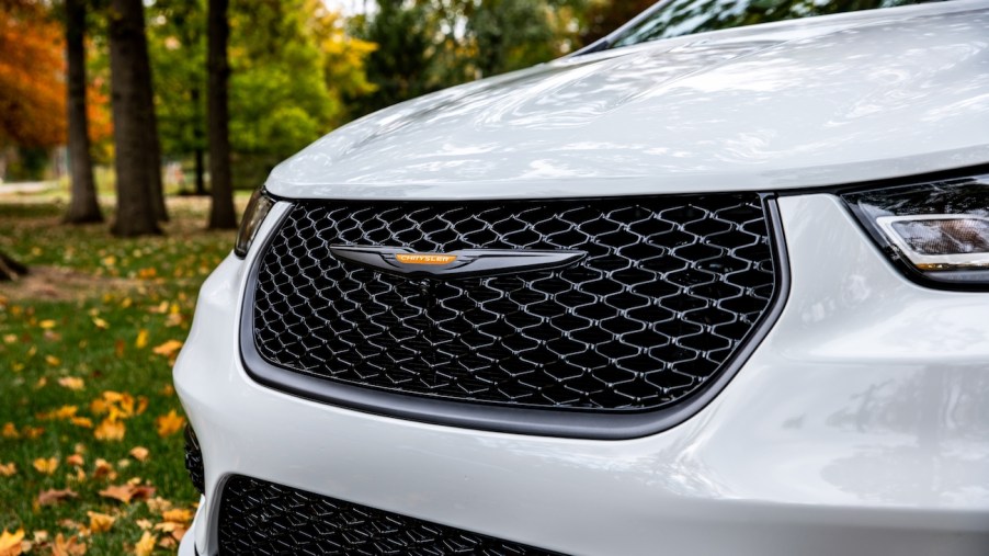The 2023 Chrysler Pacifica Road Tripper features unique exterior Brilliant Orange badging, wheel accents and graphics. White Chrysler minivan front grille.