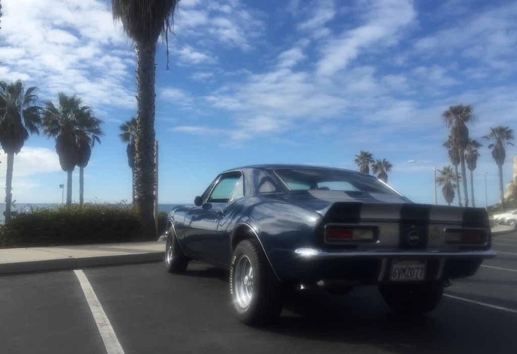 A Chevrolet Camaro, a car that demands classic car insurance, sits by the coast.
