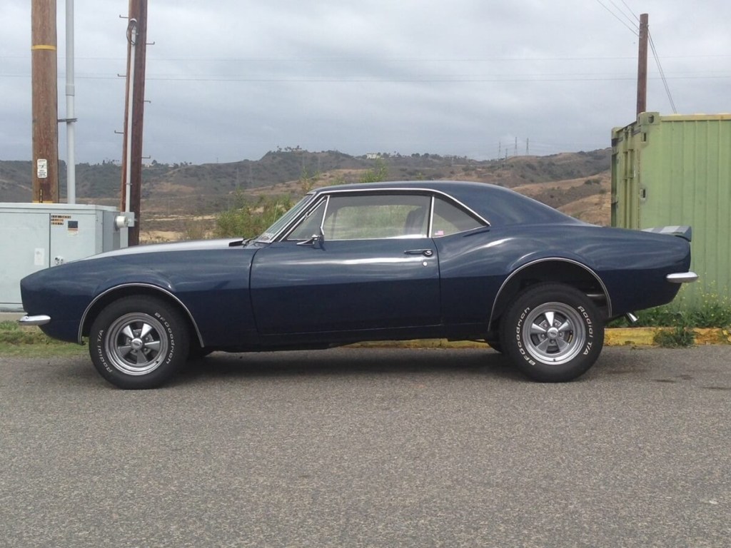 A blue classic car, an old Camaro, is used as a daily driver instead of a toy with classic car insurance.