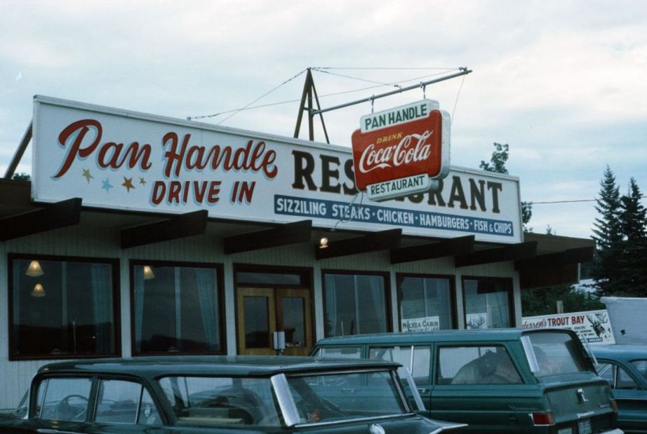 Cars parked outside of a drive-in restaurant.