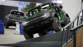 People drive a Ford Bronco through a maneuverability obstacle at the 2023 North American International Detroit Auto Show. The Ford Bronco has the best SUV resale value