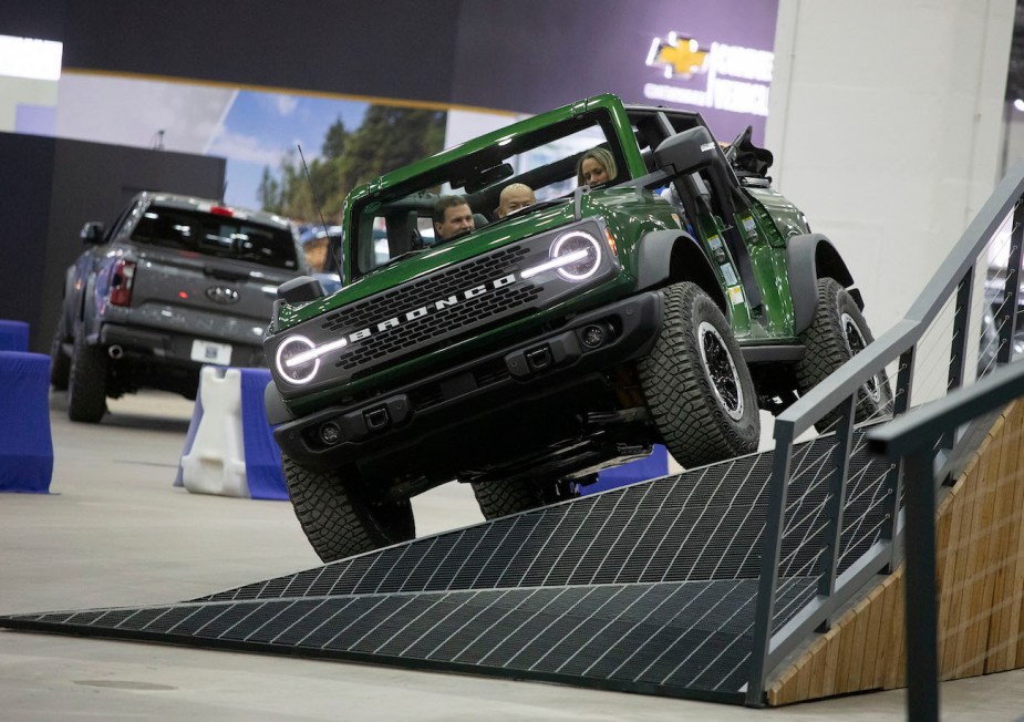 People drive a Ford Bronco through a maneuverability obstacle at the 2023 North American International Detroit Auto Show. The Ford Bronco has the best SUV resale value