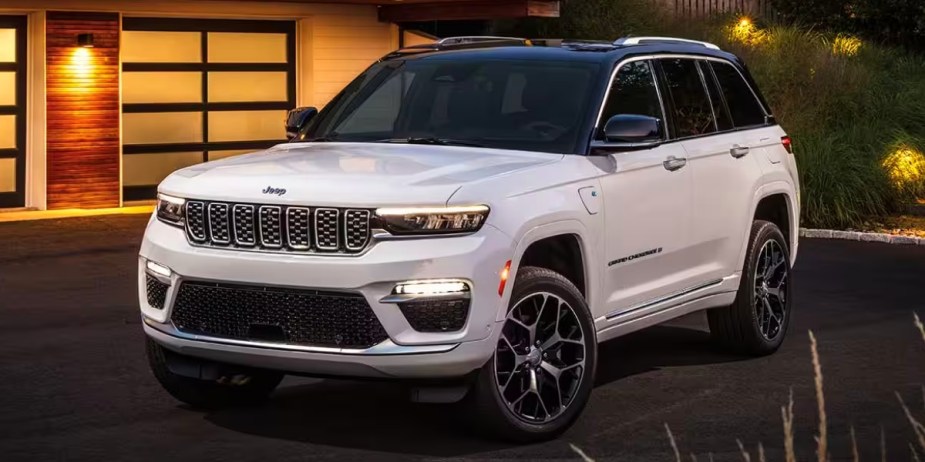 A white 2023 Jeep Grand Cherokee midsize SUV is parked in a driveway.
