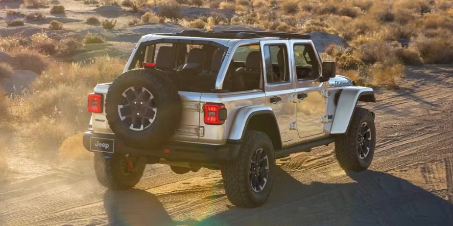A gray Jeep Wrangler 4xe small plug-in hybrid SUV is driving off-road. 