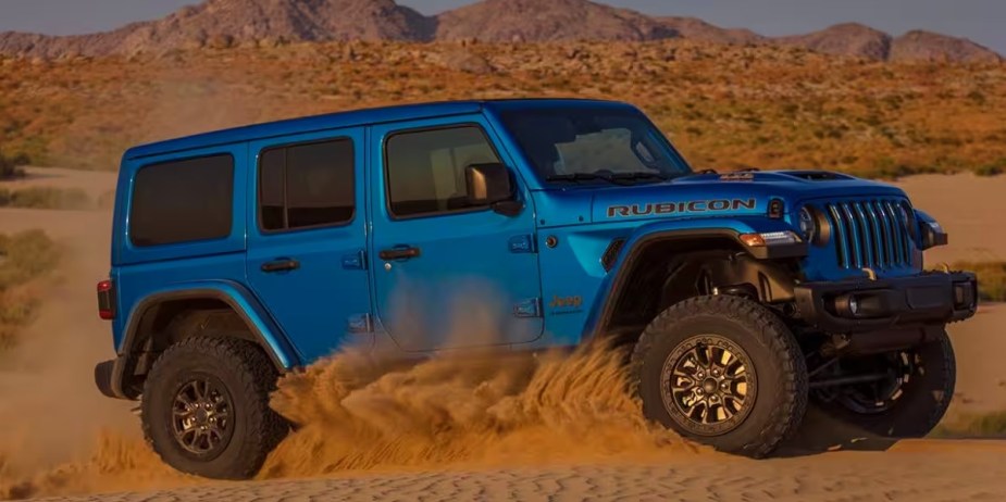 A blue Jeep Wrangler 4xe small plug-in hybrid SUV is driving off-road.