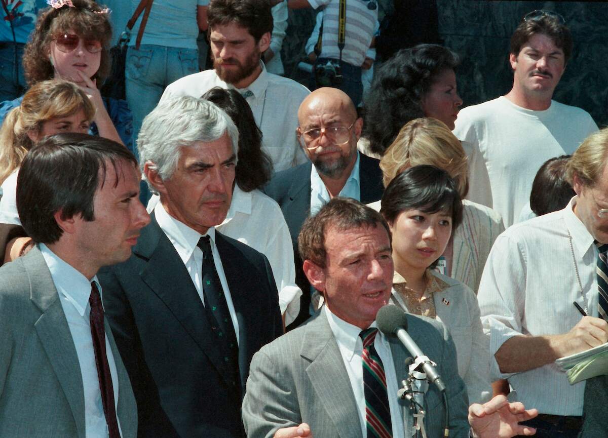 John DeLorean listens to his attorney Howard Weitzman speak to media after acquittal outside the U.S. Federal Courthouse in Los Angeles on Aug. 16, 1984