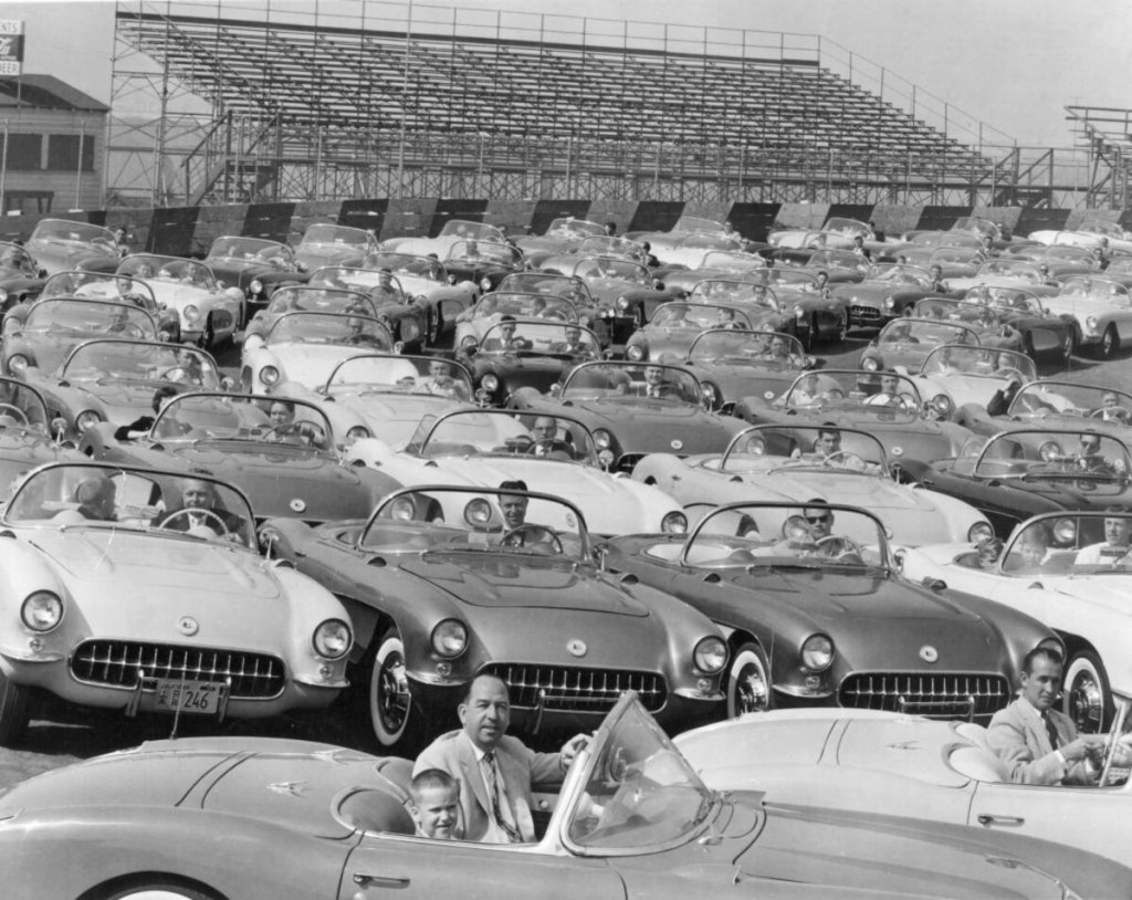A gang of new 1956 Corvettes at racetrack with Chevrolet executives